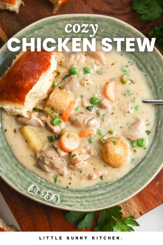 overhead view of a large bowl of rich, creamy chicken stew, set on a table. There is a fluffy dinner roll on the edge of the bowl. Text overlay says "cozy chicken stew"