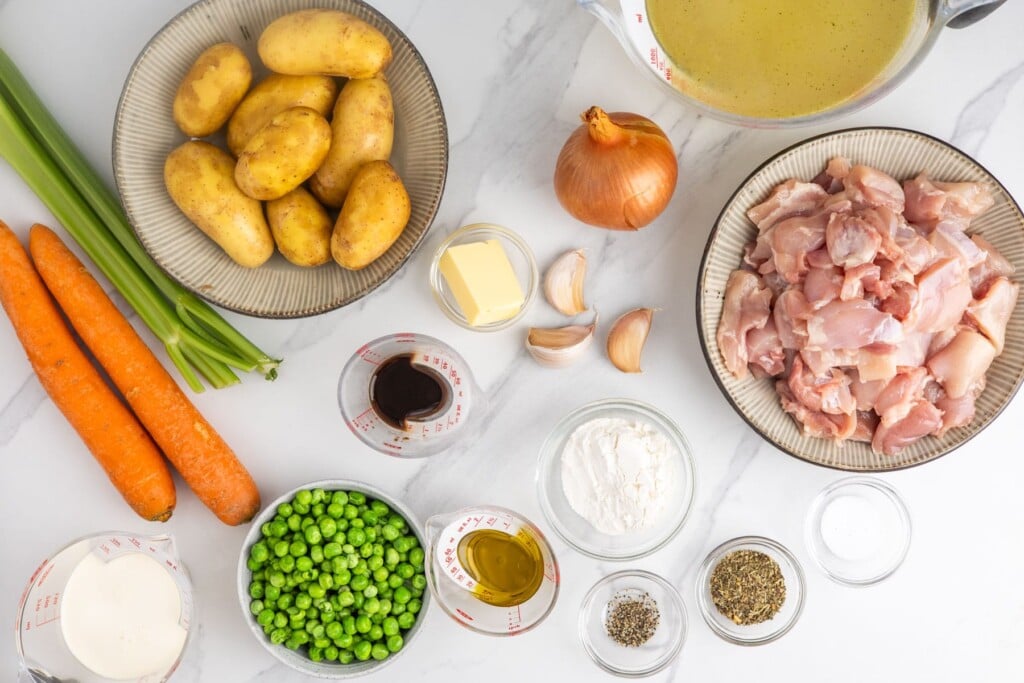 Ingredients for classic stovetop chicken stew with potatoes, carrots, and peas.