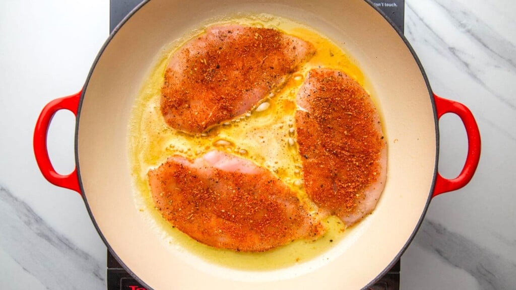 chicken cutlets seasoned with cajun seasoning, searing in a pan.