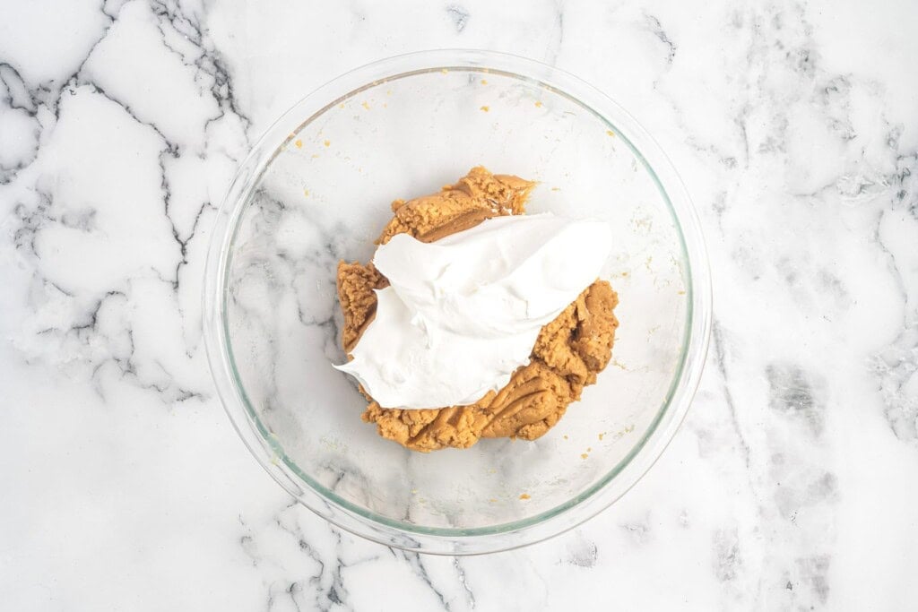 whipped topping added to peanut butter mixture in a bowl.