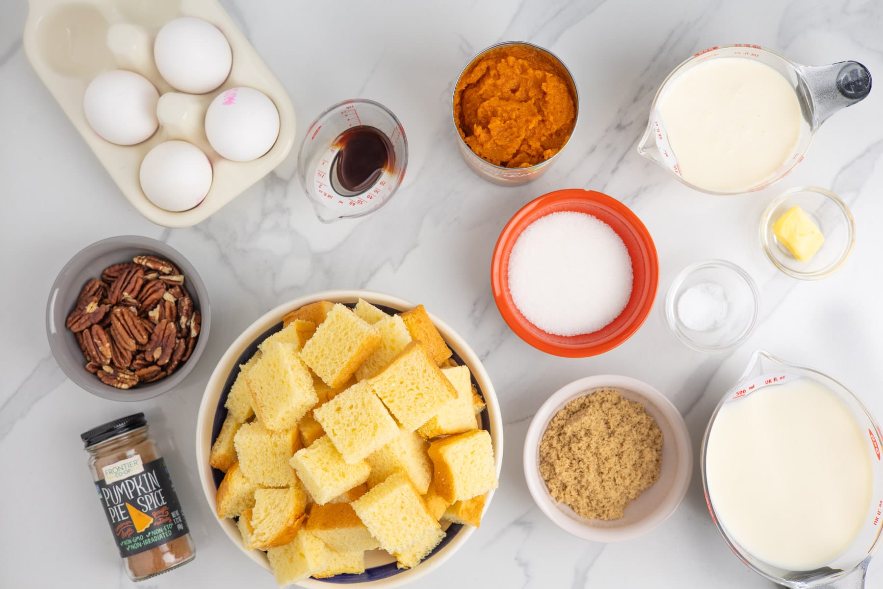 Ingredients needed for bread pudding with pumpkin puree and pumpkin pie spice.