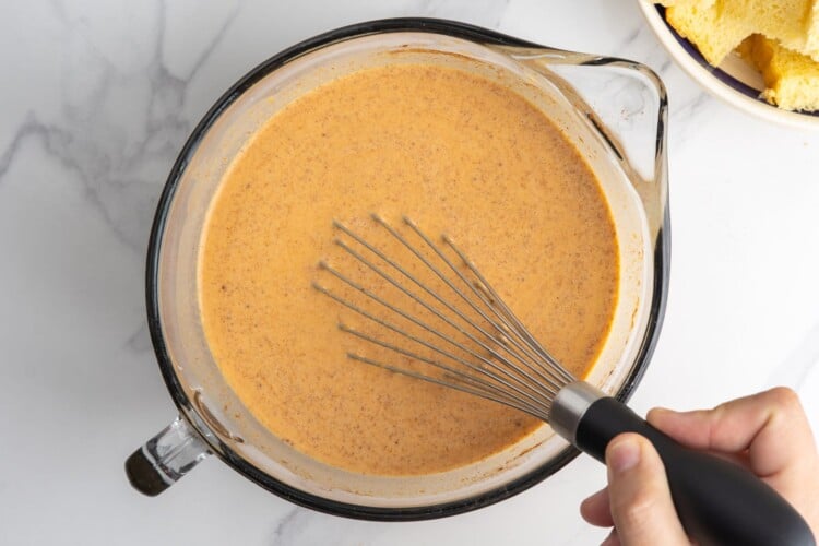 pumpkin, milk, egg mixture for bread pudding, whisked in a large glass bowl.