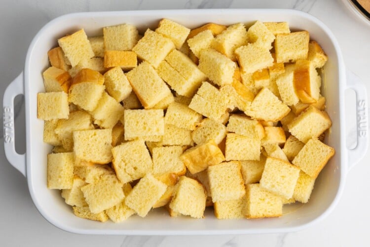 cubed brioche bread in a buttered casserole dish.