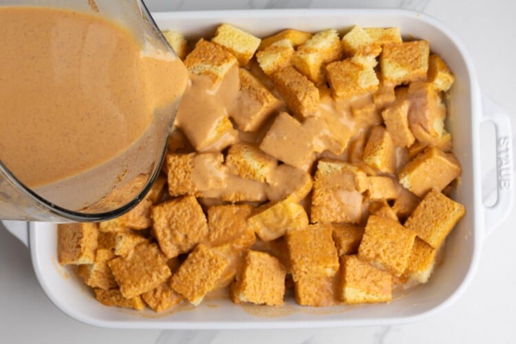 pumpkin custard poured over a pan of cubed brioche bread.