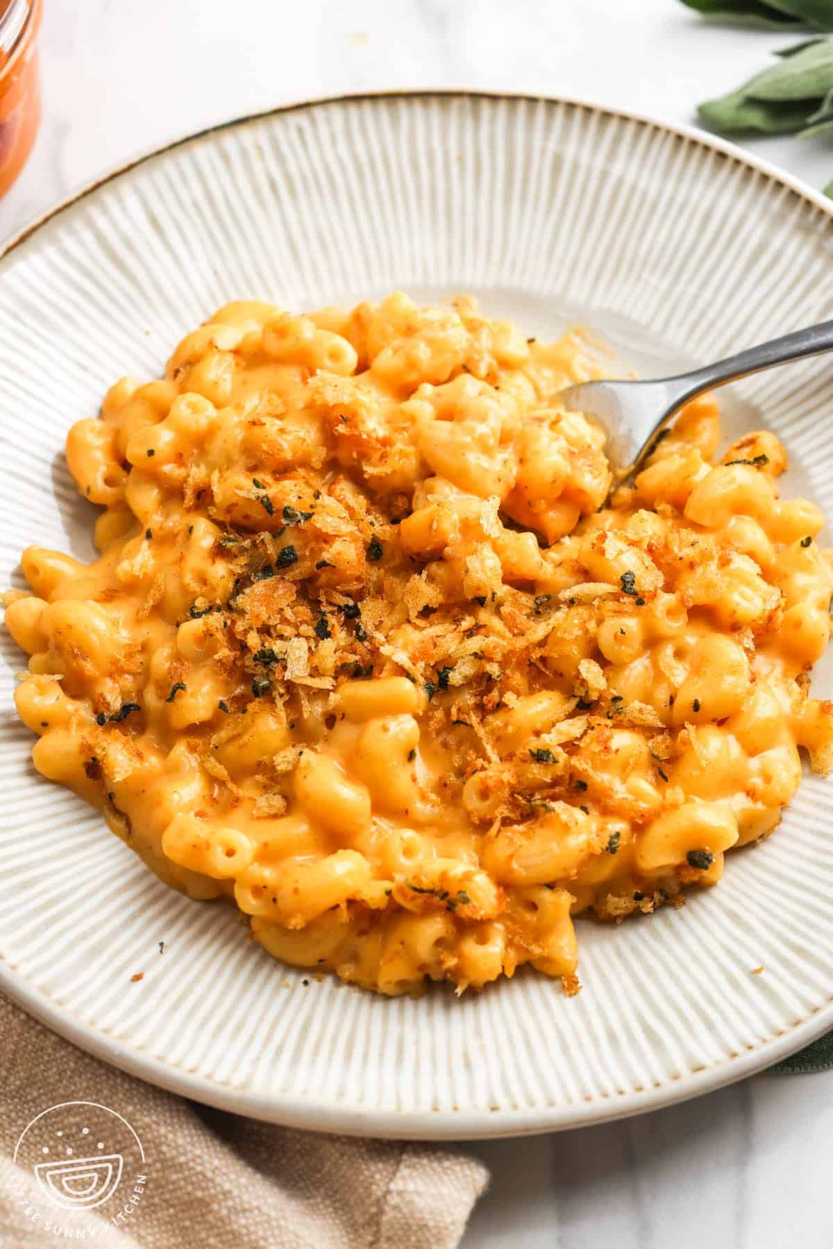 a white ceramic plate of pumpkin mac and cheese on a counter.