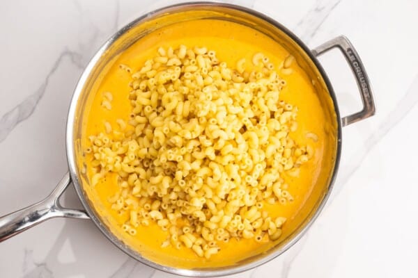 cooked macaroni added to a large saucepan of creamy pumpkin cheese sauce.