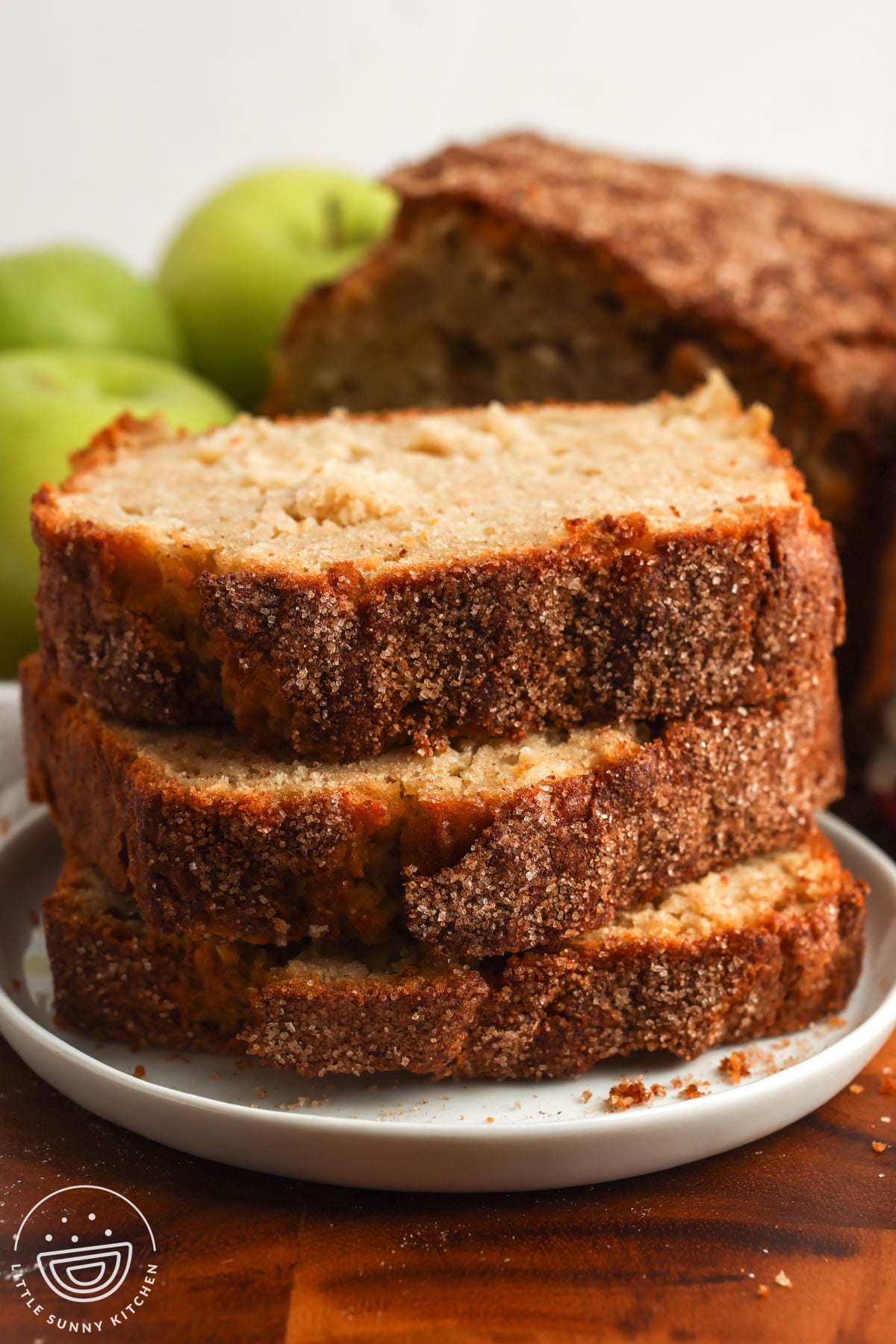 three slices of apple bread on a plate, showing the top of the loaf with a thick cinnamon sugar coating.