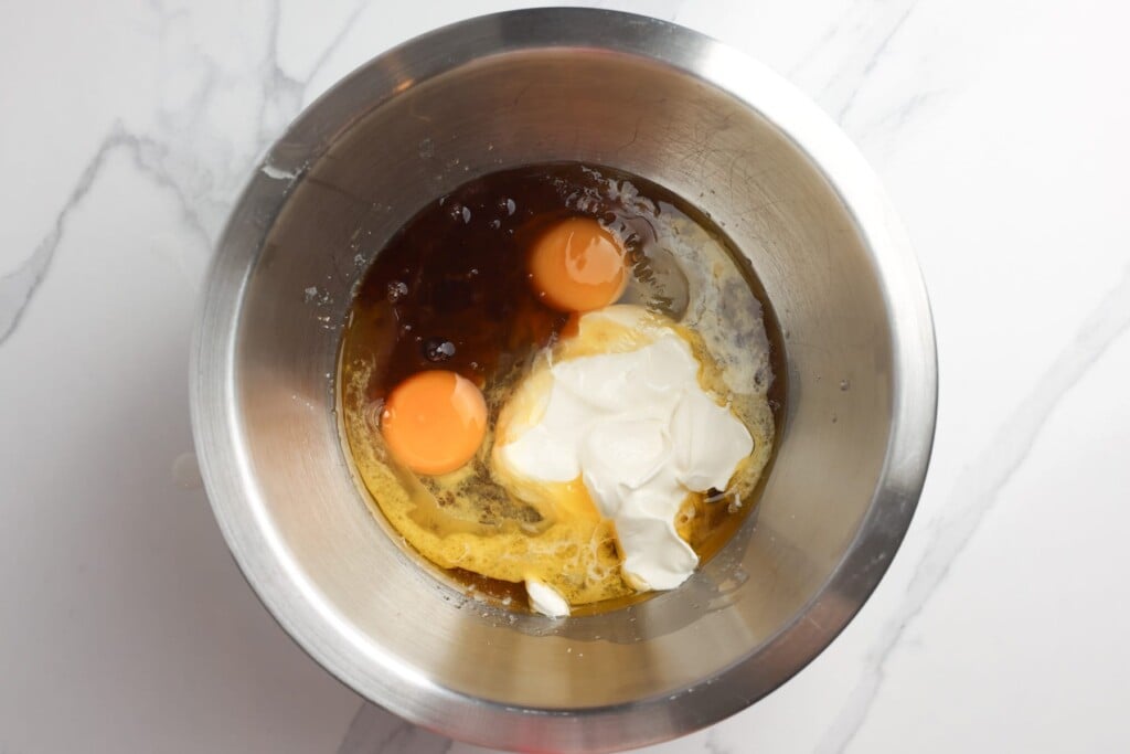 eggs, sour cream, vanilla, and melted butter in a metal mixing bowl for apple bread.