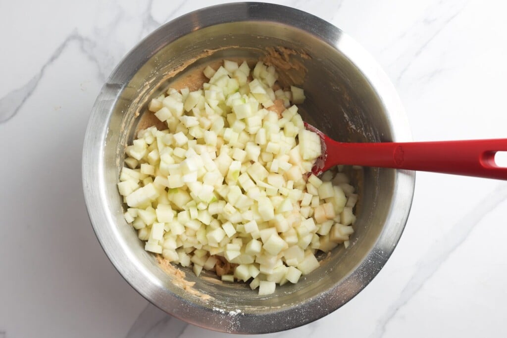 cubes of granny smith apple folded into the batter for apple bread.