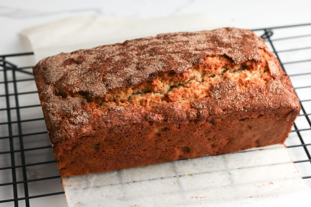 Baked apple bread lifted out of its pan and placed on a wire rack to cool.