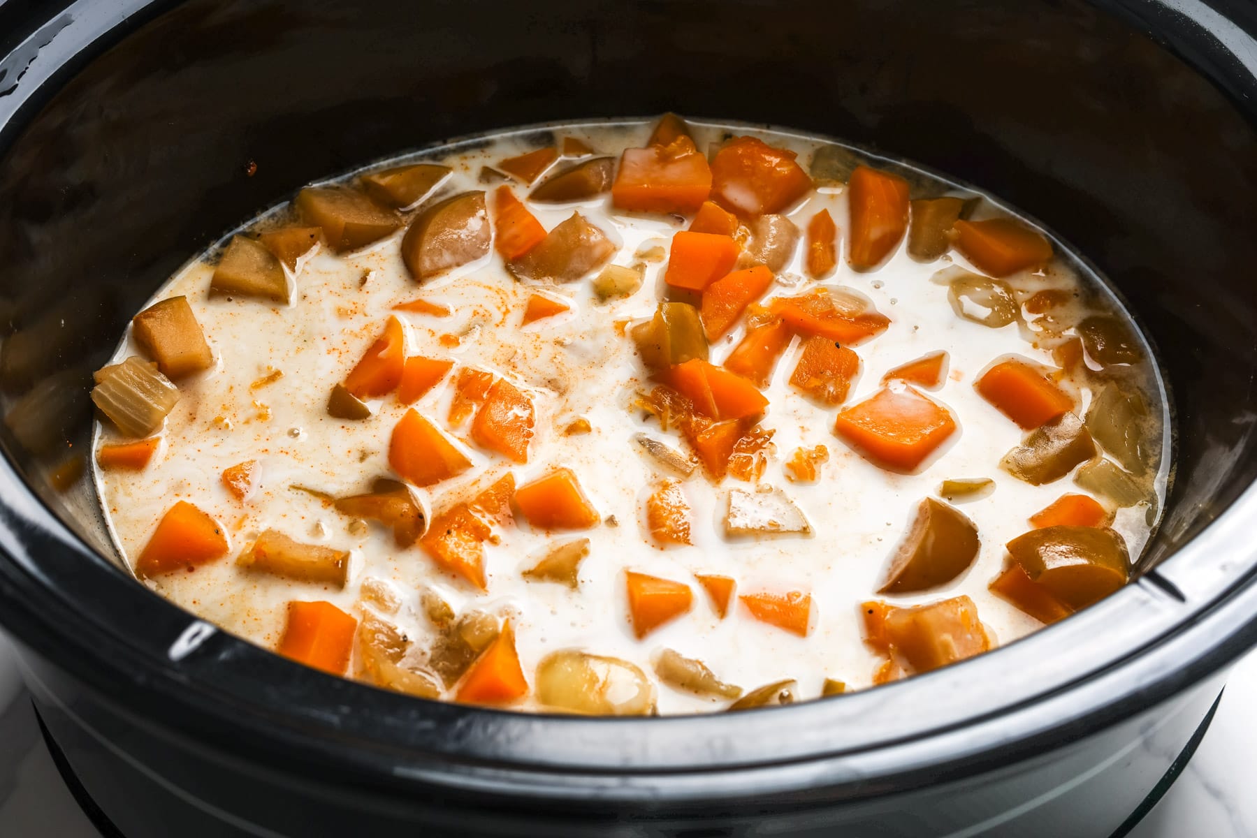 Coconut milk stirred into the cooked butternut squash and apple mixture in the slow cooker before blending.