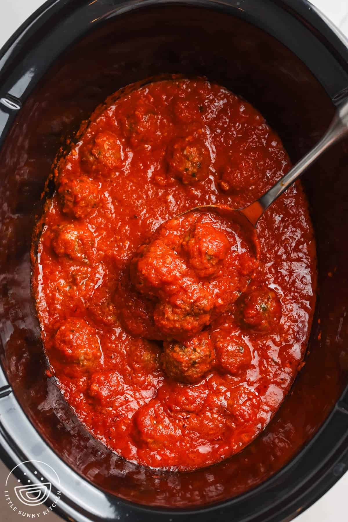 cooked meatballs in sauce in a crock pot, viewed from overhead.