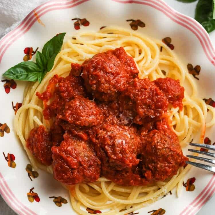 Slow cooker meatballs served over spaghetti with grated Parmesan