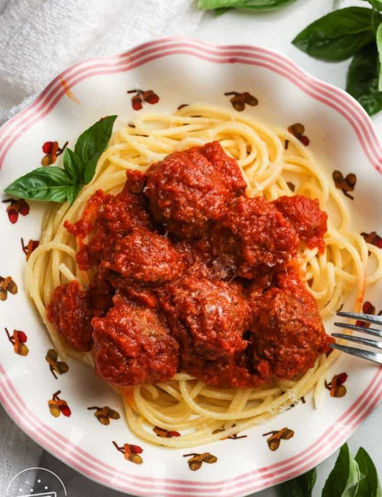 Slow cooker meatballs served over spaghetti with grated Parmesan