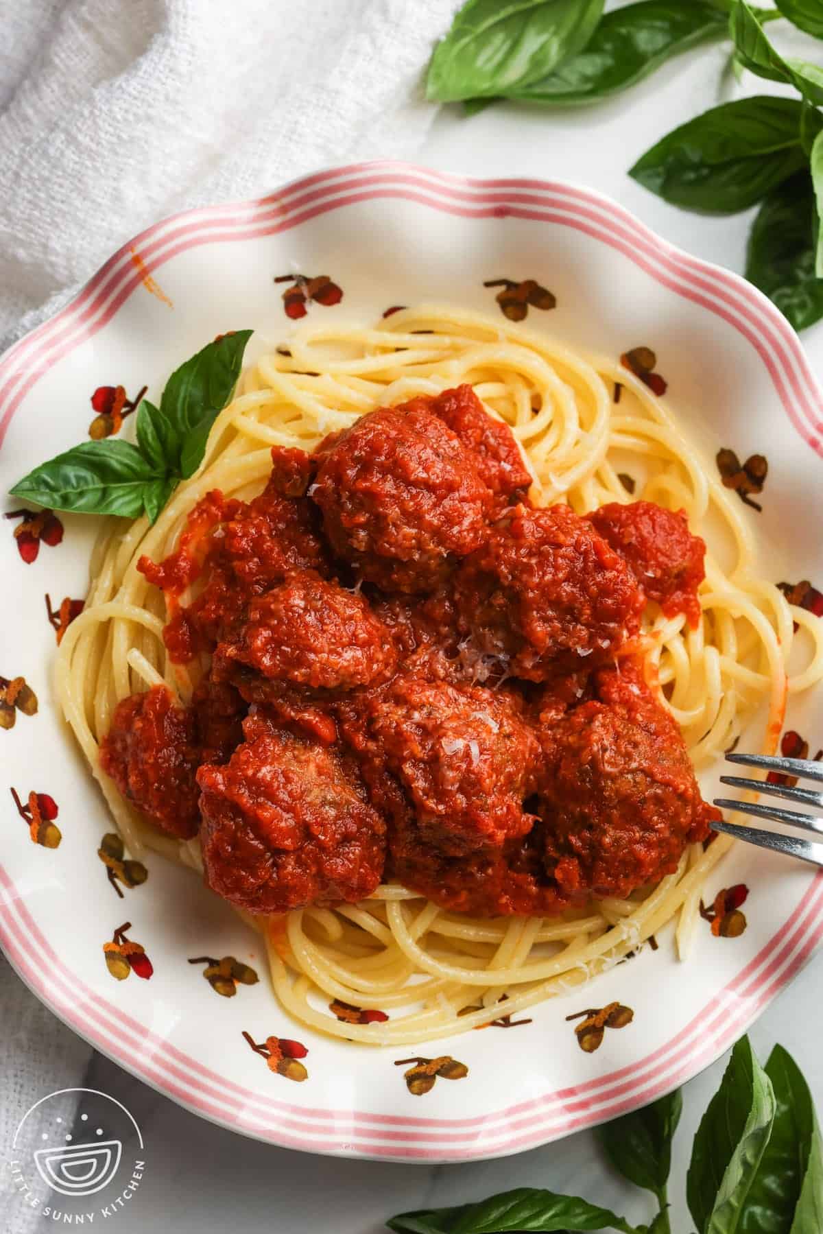 Slow cooker meatballs served over spaghetti with grated Parmesan