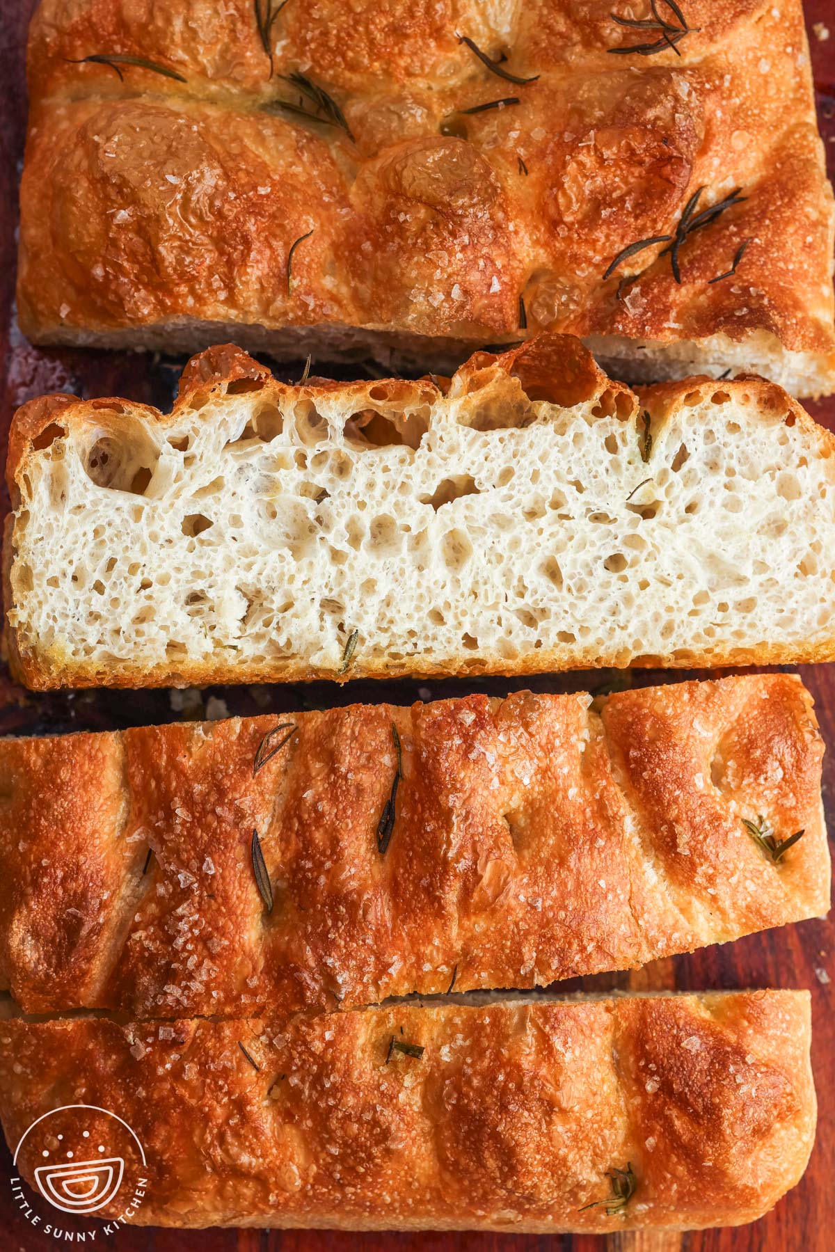 overnight focaccia cut into thick slices on a wooden board, showing an open airy crumb and dimpled crust