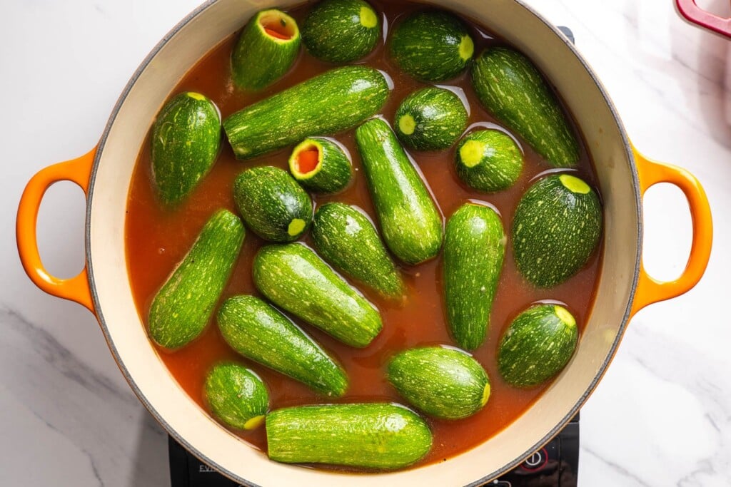 Stuffed kousa arranged snugly in the tomato sauce in a Dutch oven.
