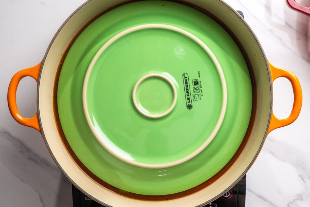 An upside down plate set on top of the kousa to keep them under the sauce.