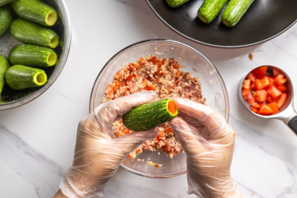Filling a zucchini about three quarters full so the rice has room to expand.