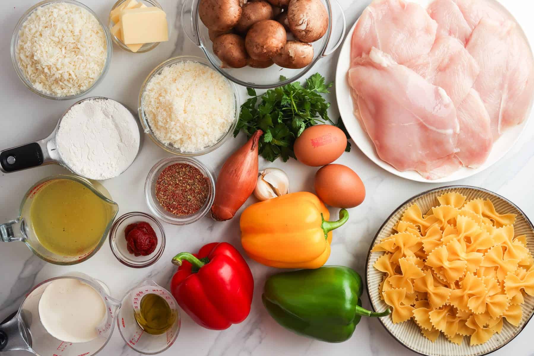 Ingredients to make Louisiana Chicken Pasta including breadcrumbs, chicken cutlets, pasta, and veggies.