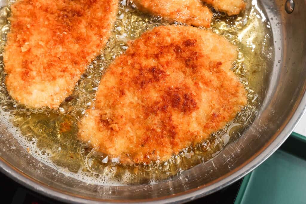 breaded chicken cutlets frying in oil.