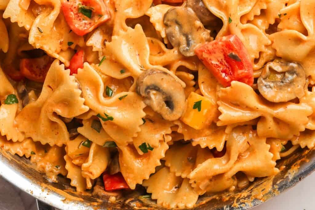 closeup of bowtie pasta coated in cajun seasoned sauce in a skillet.
