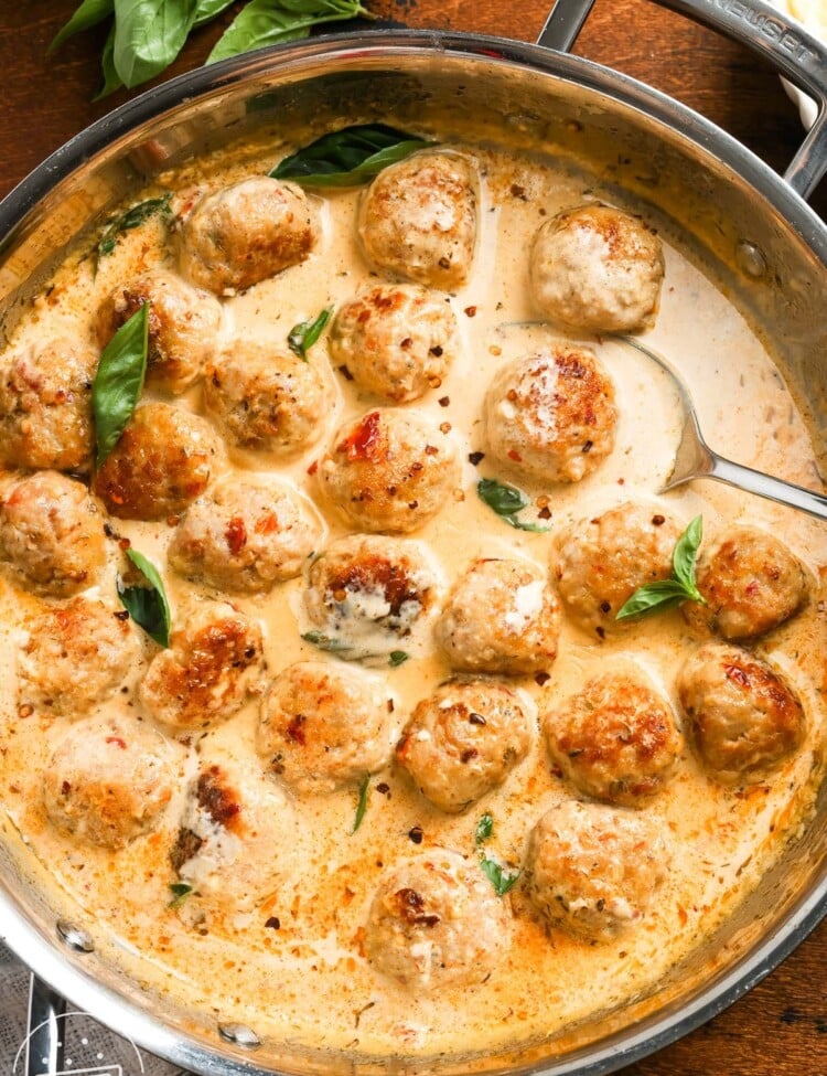 a skillet of saucy marry me chicken meatballs set on a wooden table.