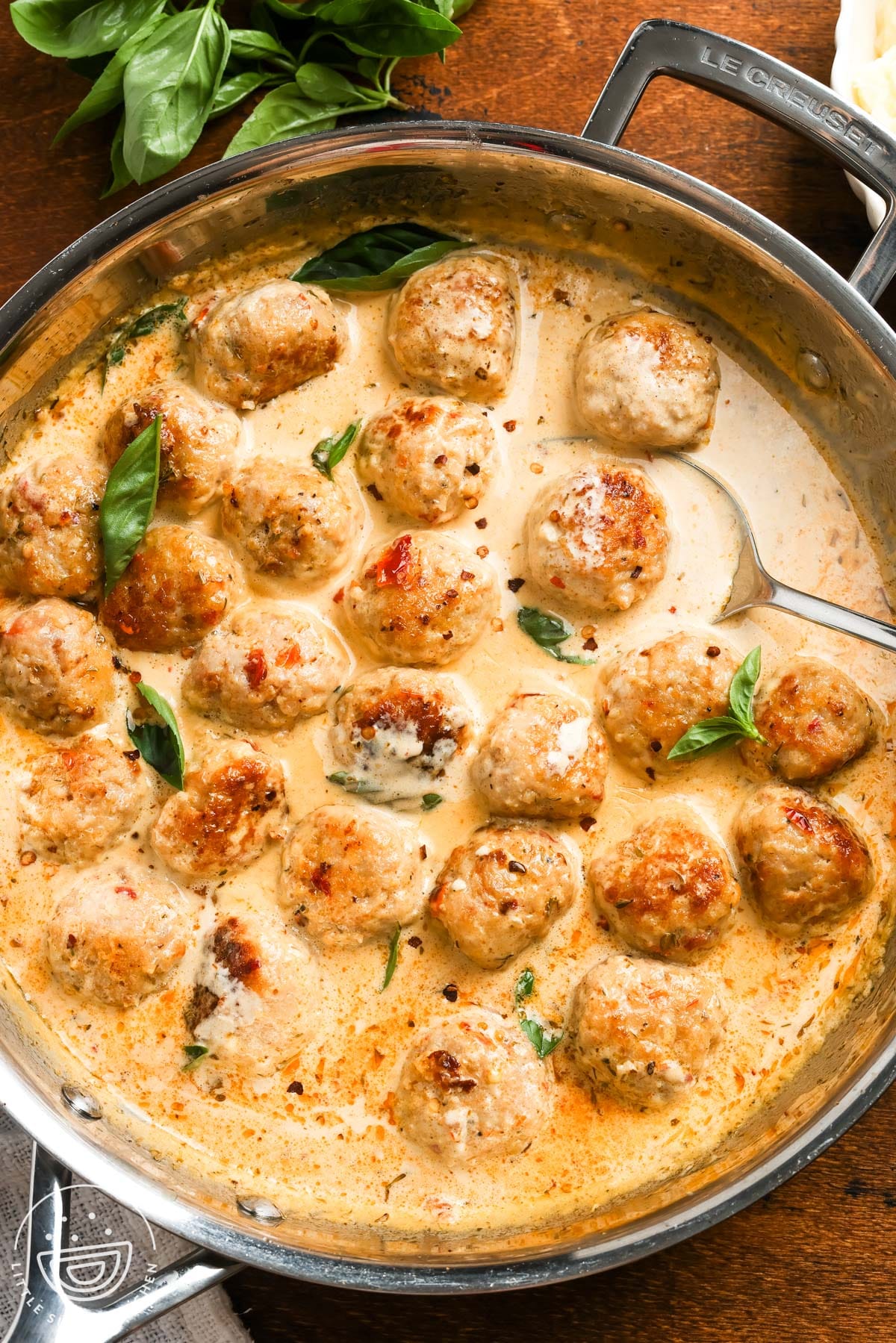 a skillet of saucy marry me chicken meatballs set on a wooden table.