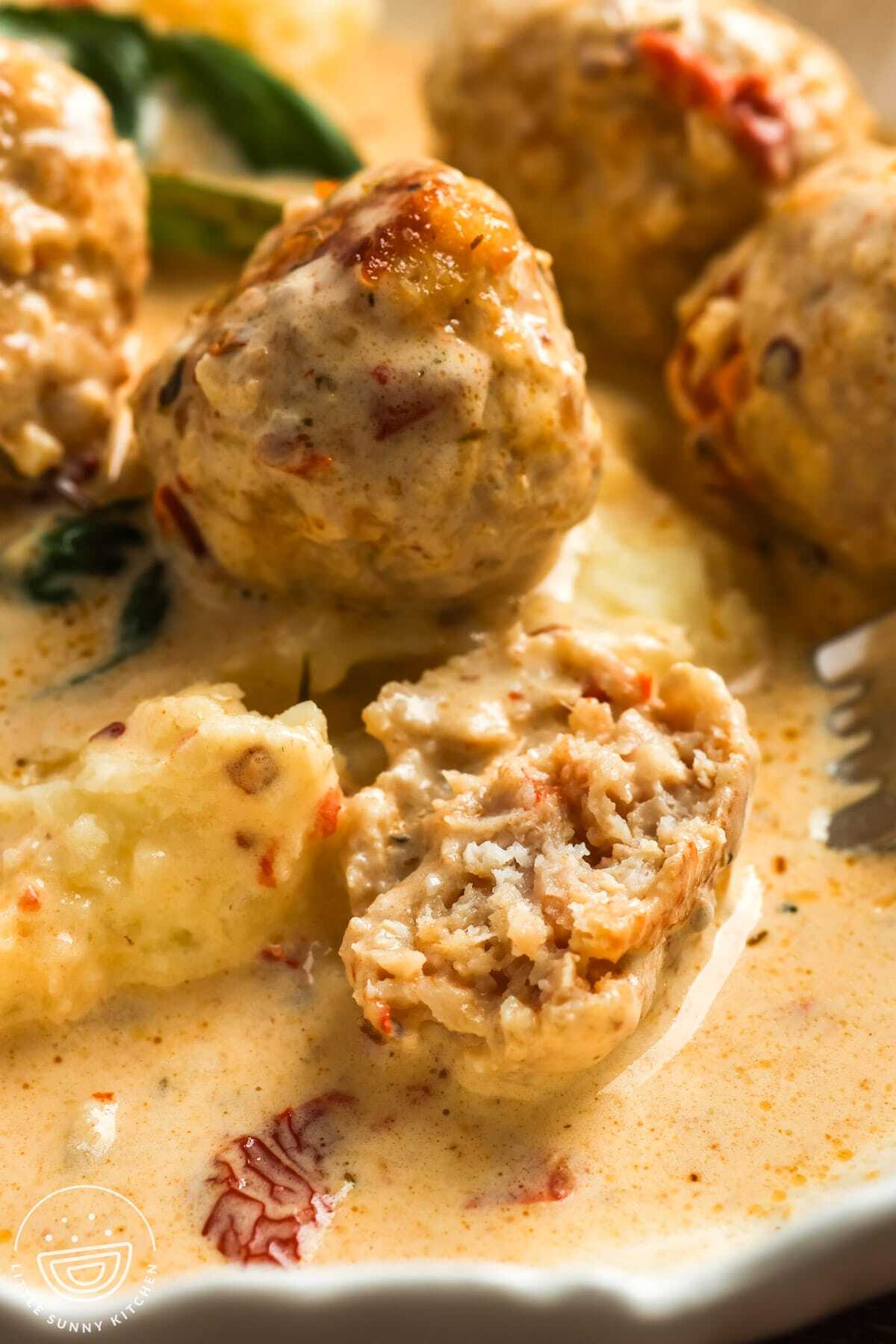 closeup of chicken meatballs. One is cut in half to show tender meat.