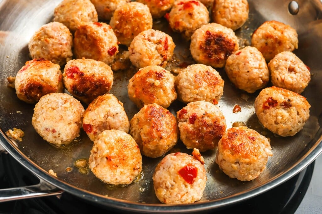 marry me chicken meatballs seared in a skillet with oil.