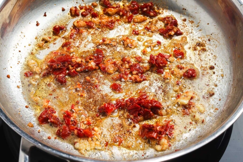 garlic and sun-dried tomatoes cooking in a skillet.