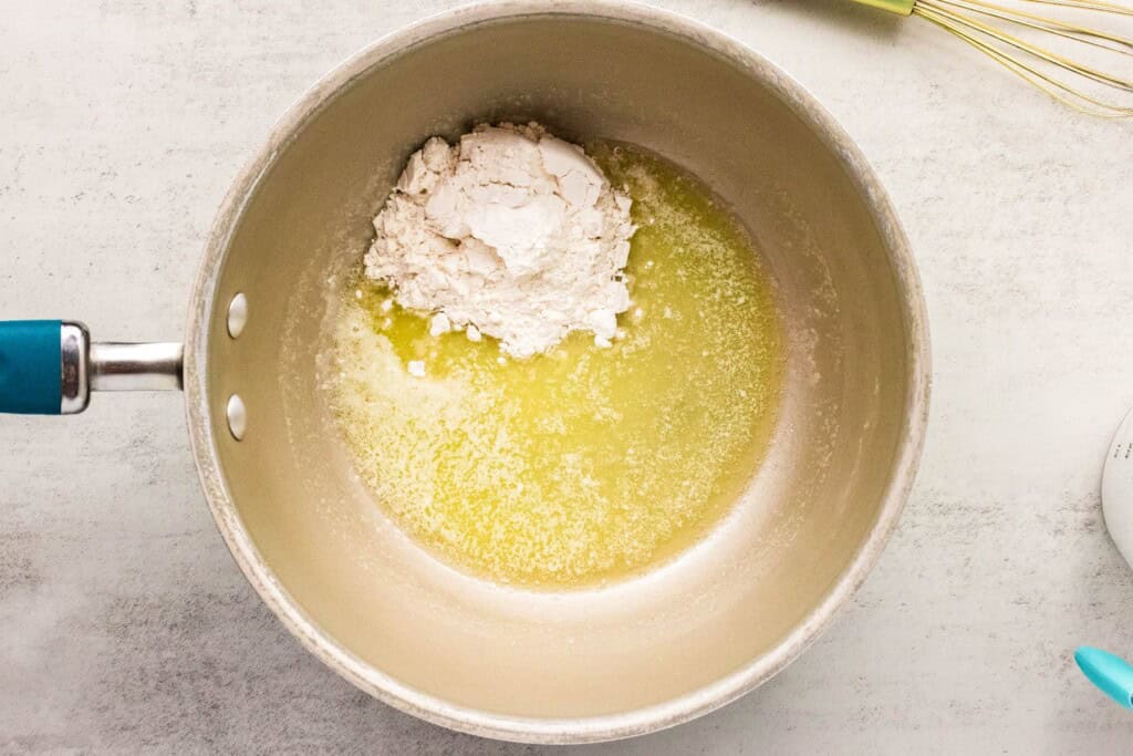 adding flour to melted butter in a saucepan for cheese sauce.