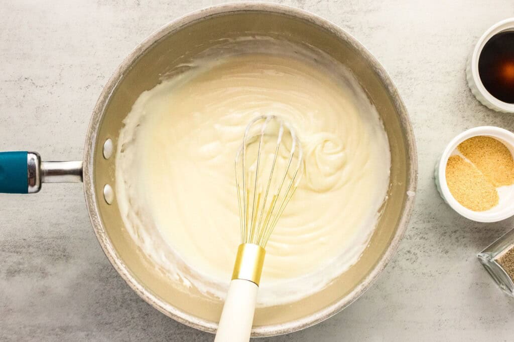 Whisking milk into butter and flour for cheese sauce.