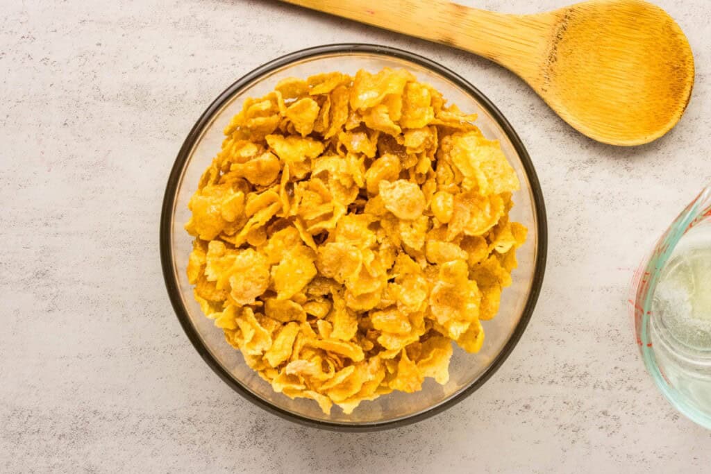 A bowl of cornflakes with melted butter in a mixing bowl.