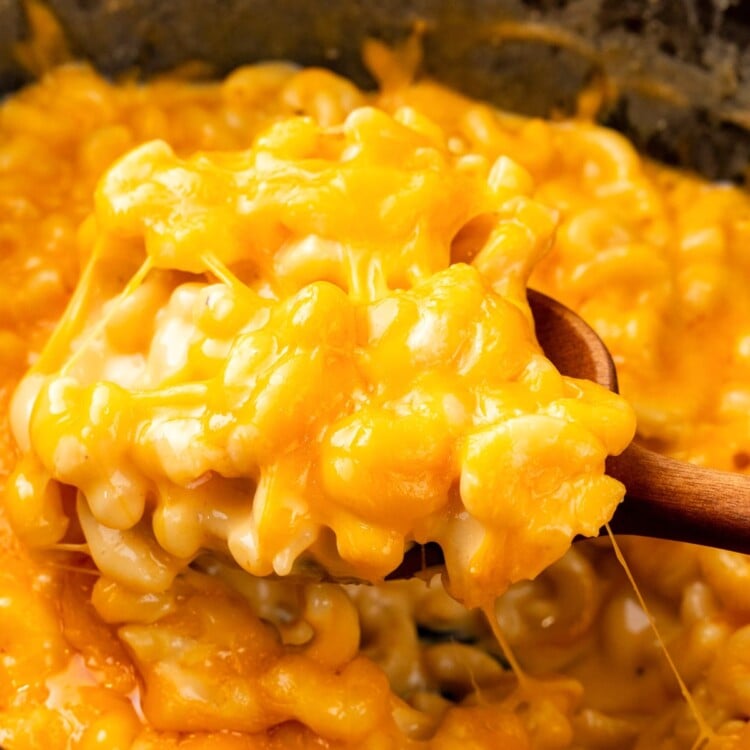 creamy mac and cheese spooned out of a slow cooker.