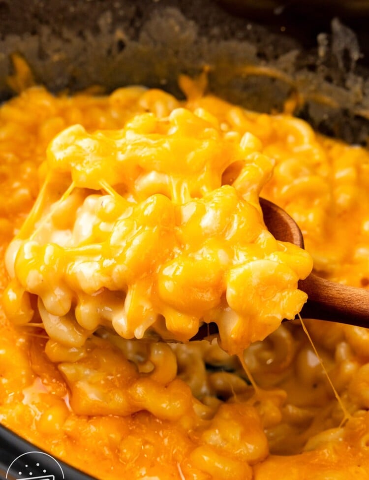 creamy mac and cheese spooned out of a slow cooker.