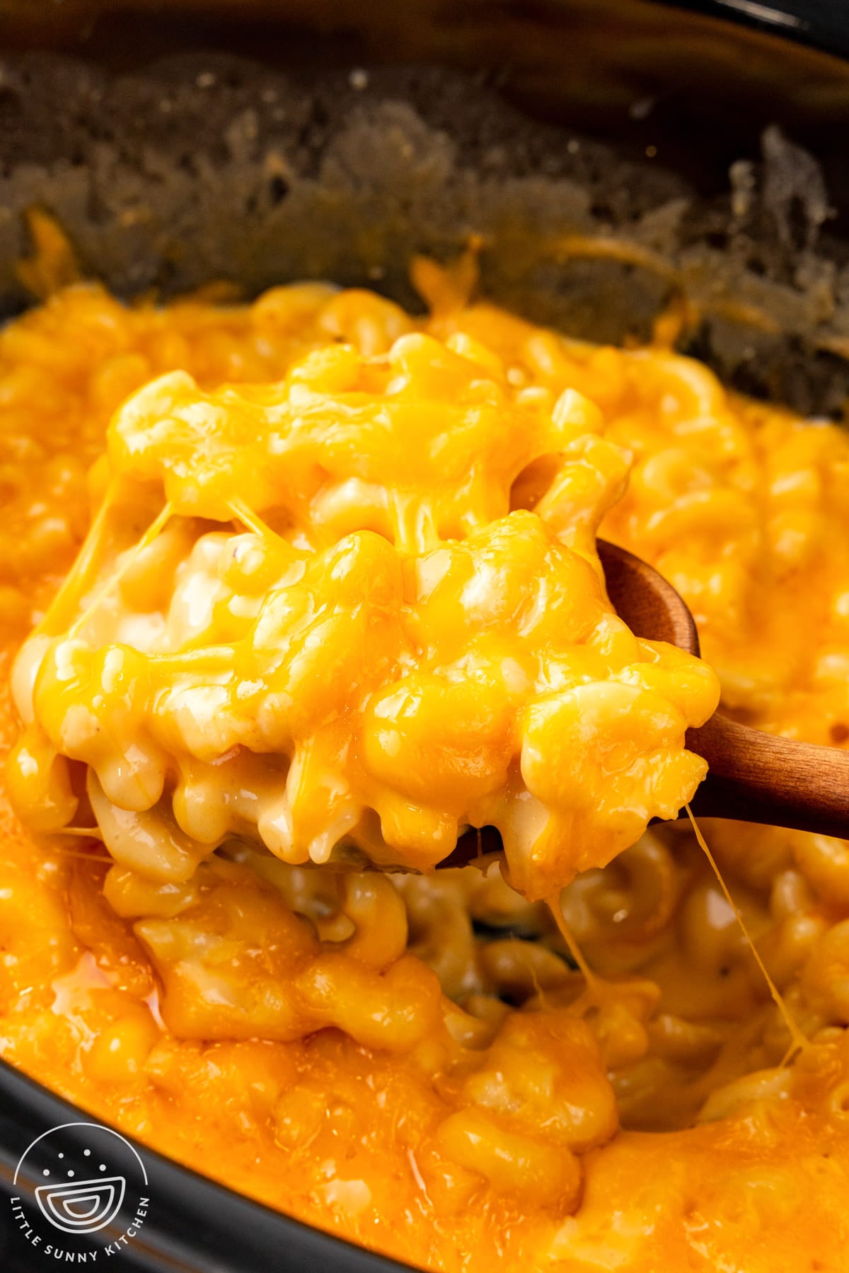 creamy mac and cheese spooned out of a slow cooker.