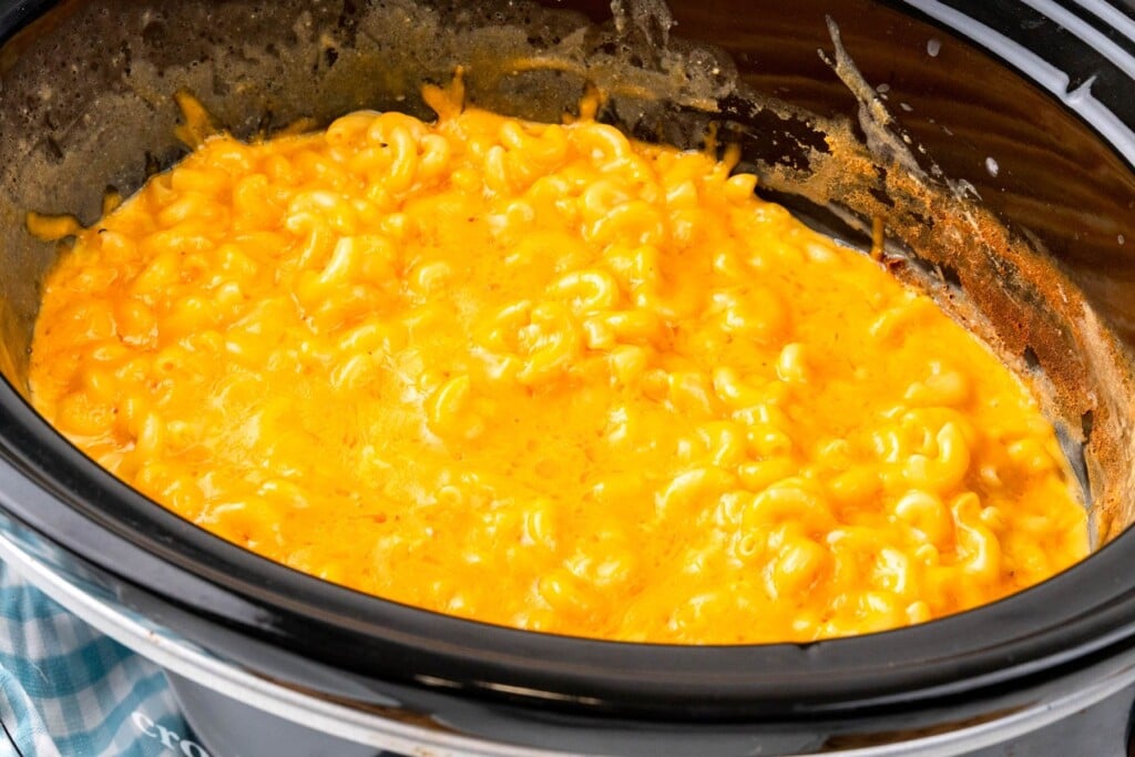 mac and cheese in a slow cooker topped with melted cheddar cheese.