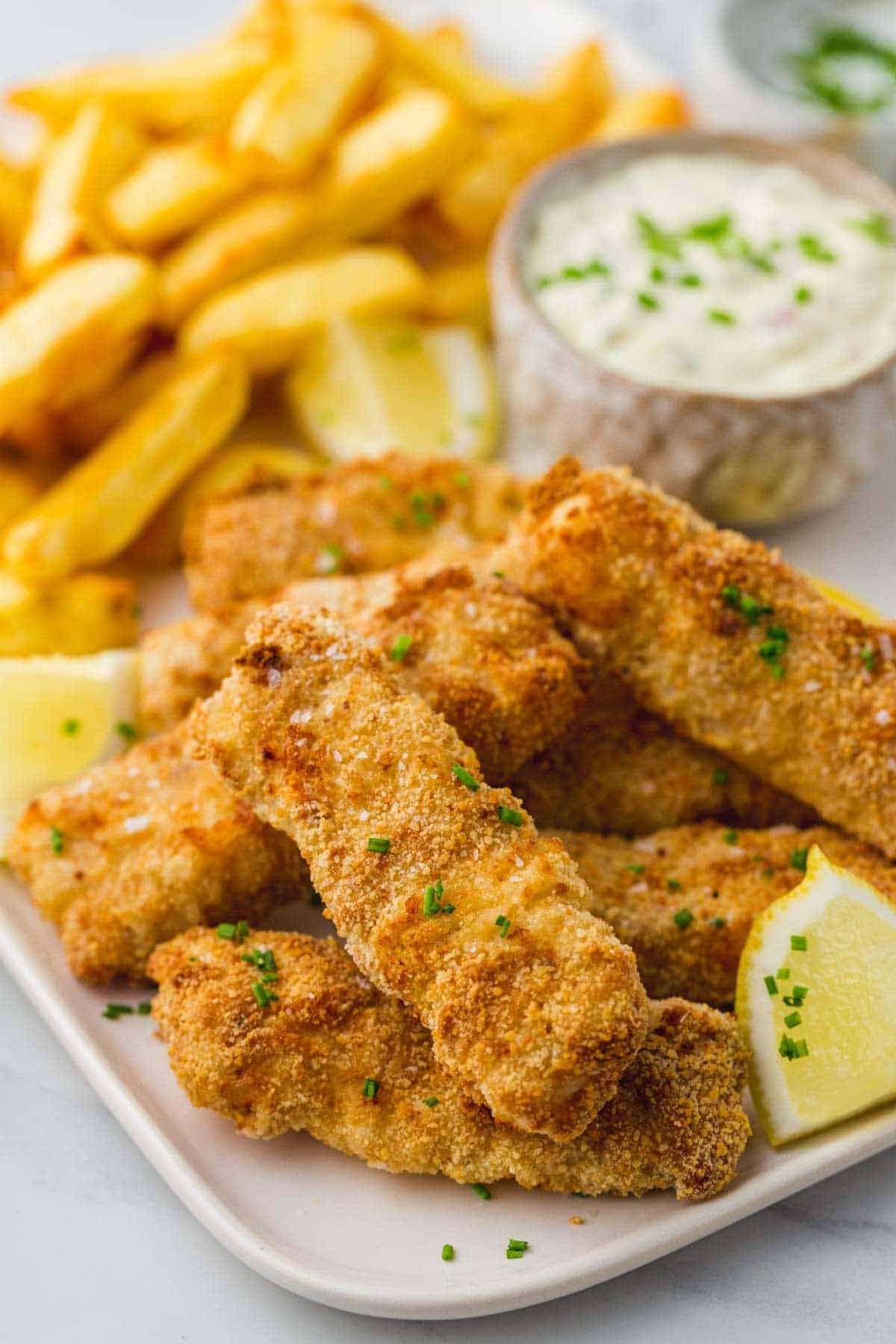 Fish sticks stacked on each other, with fresh lemon wedges on the side.