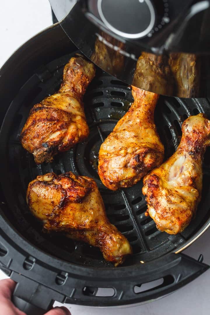 Crunchy golden air fryer drumsticks in an air fryer basket.