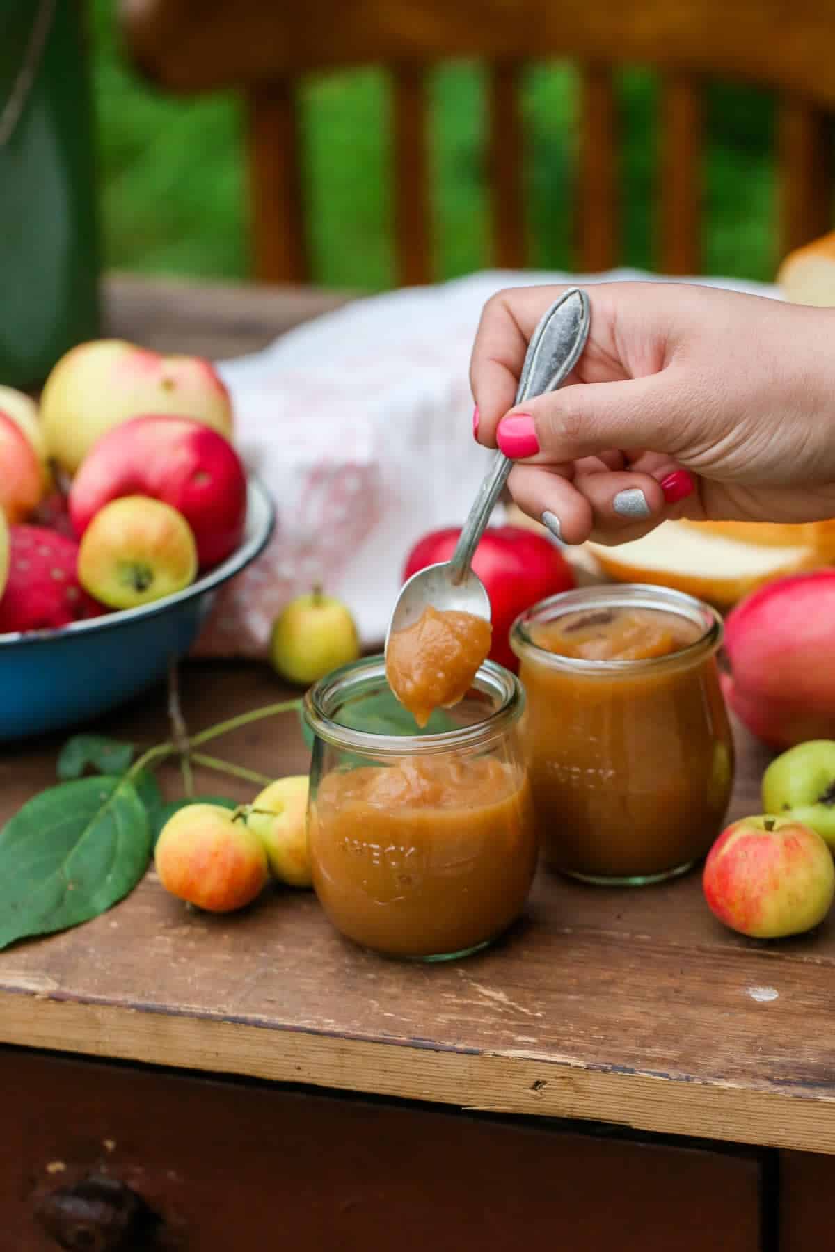 A couple small Weck jars with apple butter, and a small spoon with a hand. 