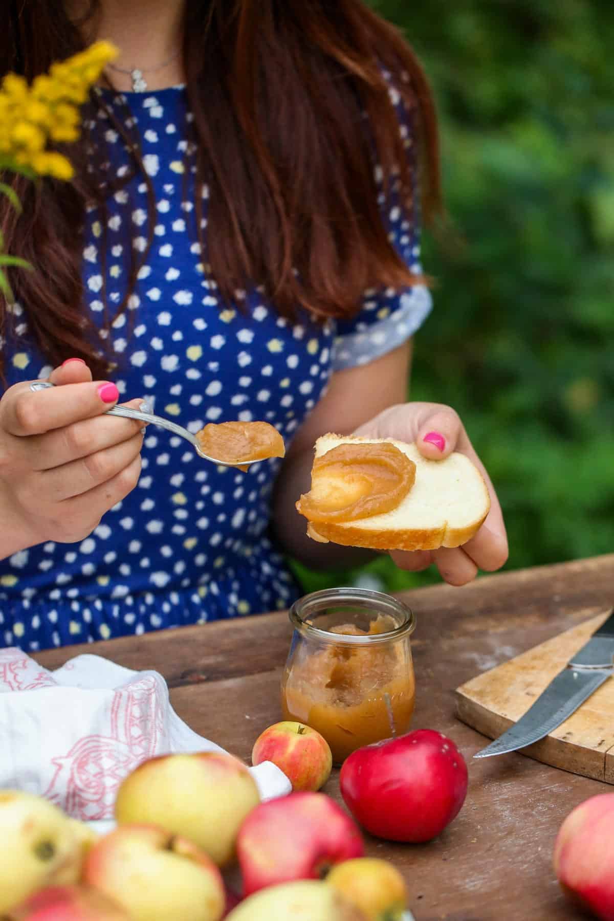 Girl spreading apple butter on toast, wearing a navy polka dot dress