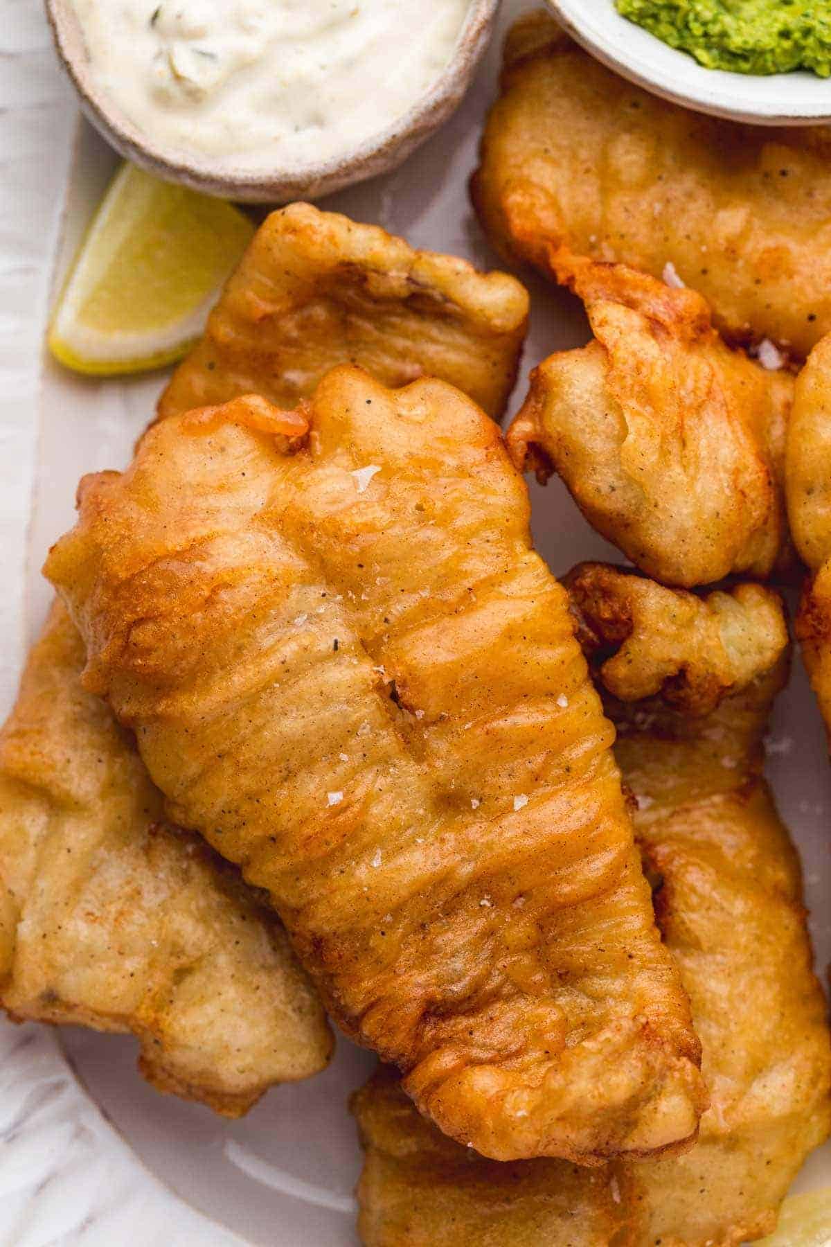 Close up of perfectly crisp golden beer battered fish served on a white plate