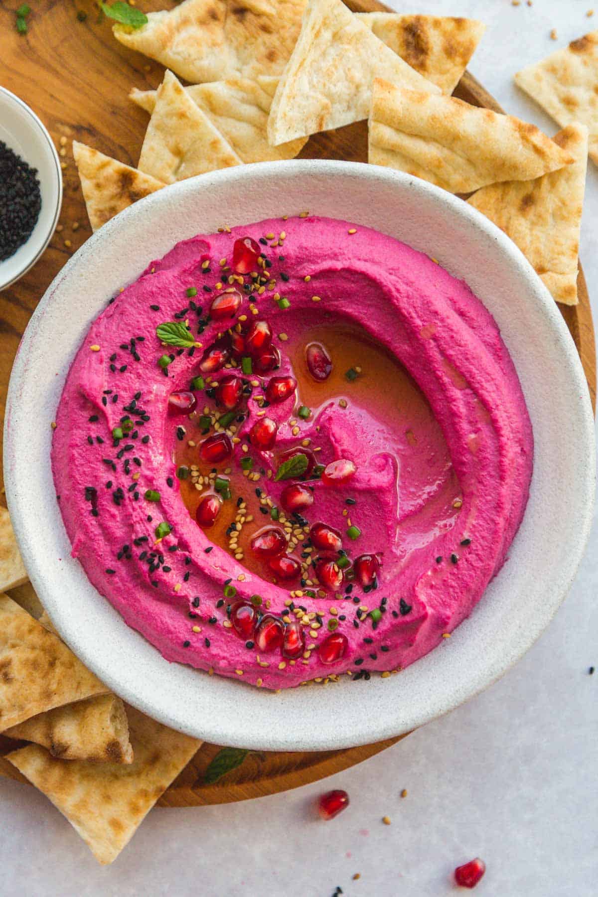 Creamy Beet Hummus in a white bowl with toasted pita triangles