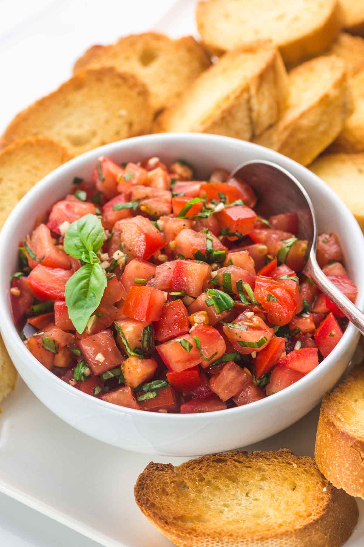 A bowl of tomato basil salad, and bruschettas in the background