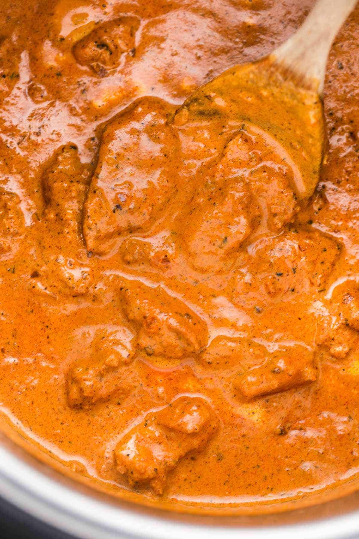 Chicken tikka masala in the instant pot with a wooden serving spoon