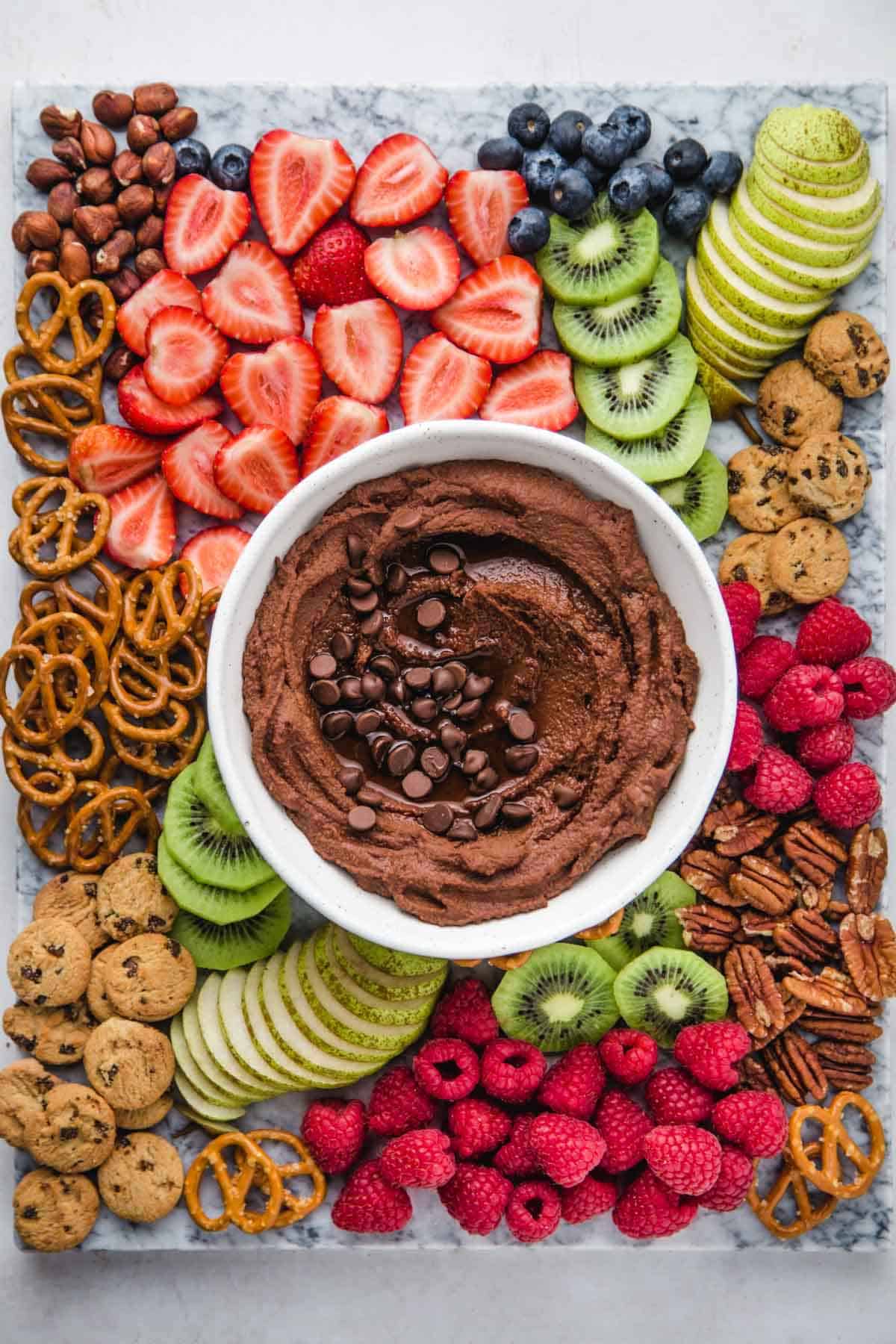 Chocolate Hummus and a fruit platter with strawberries, kiwi, blueberries, pear, pretzels, cookies, raspberries, and nuts.