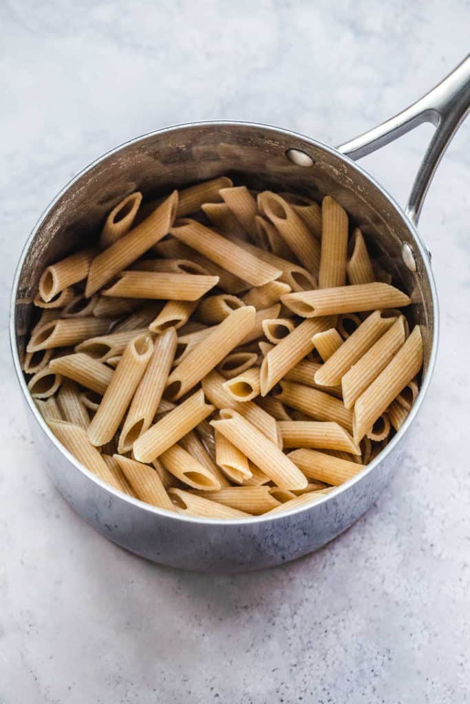 A stainless steel saucepan with cooked whole wheat pasta