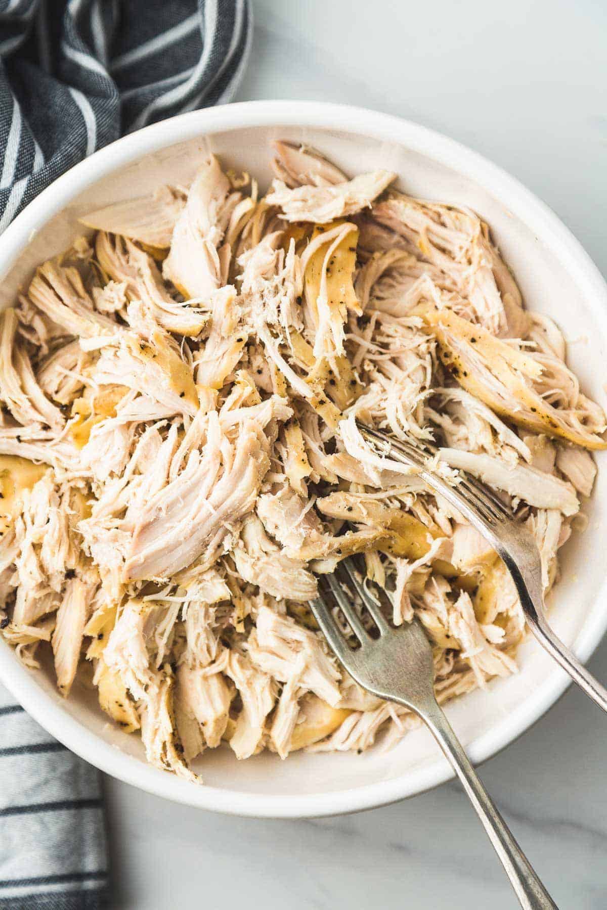 Crockpot Shredded Chicken in a white bowl with 2 forks