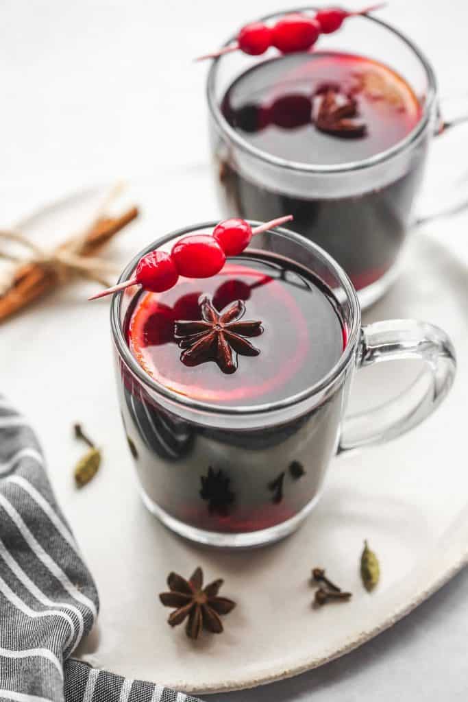 2 glass mugs with gluhwein mulled wine on a white ceramic tray